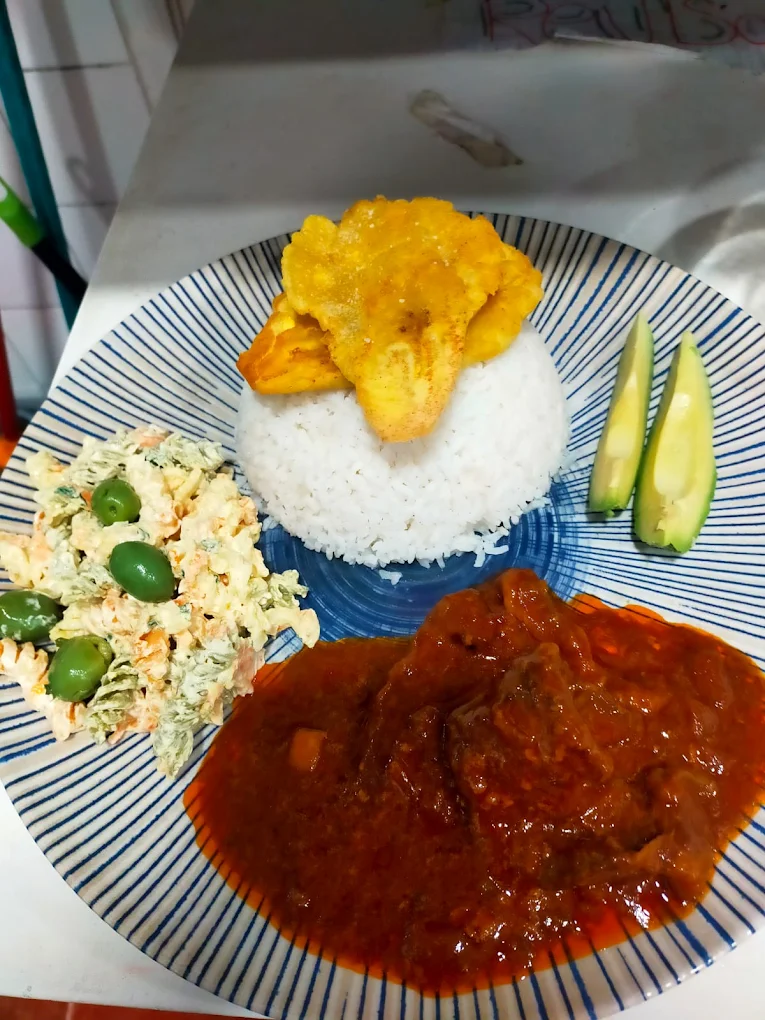 Arroz blanco con carne guisada, ensaladilla rusa, aguacate y patacones.